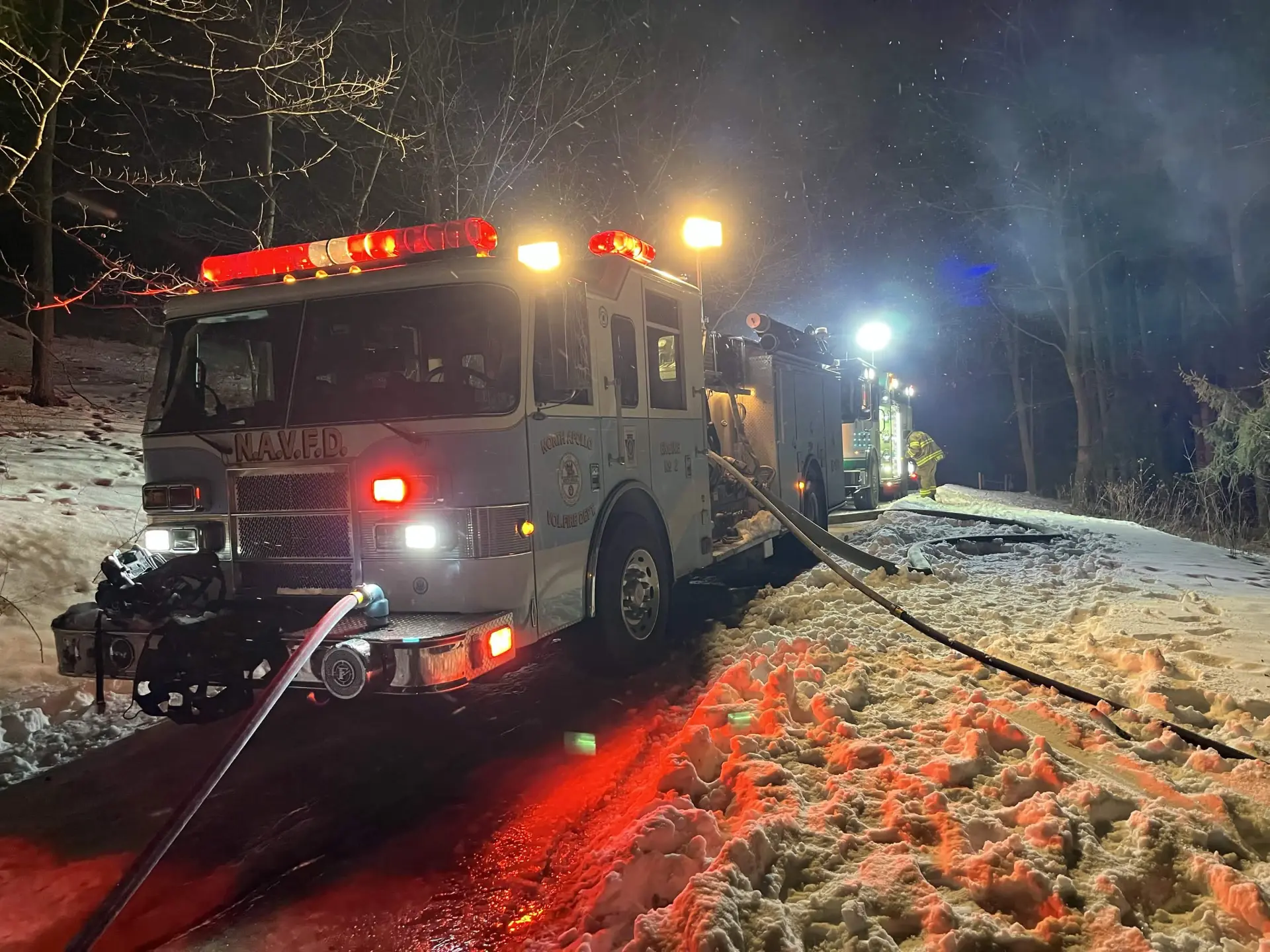 Department engine working a night incident in the snow with hose lines deployed